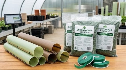 A clean, expanded product still life on a warm wooden table in a professional greenhouse workshop, showcasing several tubular tree shelters neatly stacked next to multiple clearly labeled commercial-grade slow-release fertilizer bags (branded "GREENWOOD NURSERY - STARTER PACK"), and several spools of professional green tree tie tape, under bright, diffused daylight.
